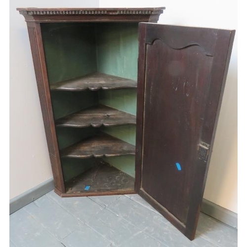 755 - A Georgian mahogany wall hanging corner cupboard with dentil cornice, flanked by reeded columns, hou... 