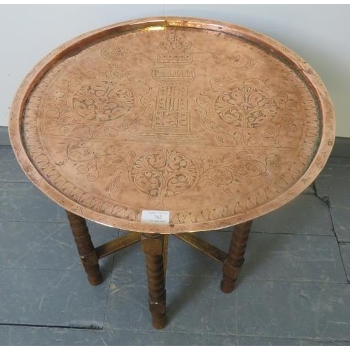 762 - An Islamic brass topped Benares style table, featuring hand tooled designs, on folding ball turned o... 