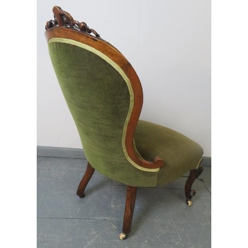 765 - A Victorian walnut spoonback nursing chair, with ornately carved and pierced cornice, upholstered in... 