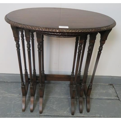 820 - An Edwardian mahogany nest of three oval tables by Maple & Co, with foliate carved borders, on turne... 
