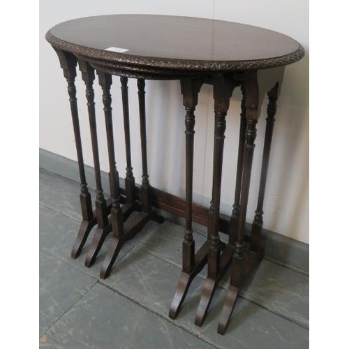 820 - An Edwardian mahogany nest of three oval tables by Maple & Co, with foliate carved borders, on turne... 