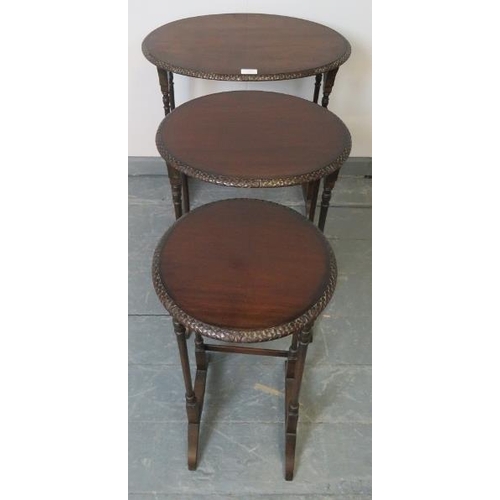 820 - An Edwardian mahogany nest of three oval tables by Maple & Co, with foliate carved borders, on turne... 