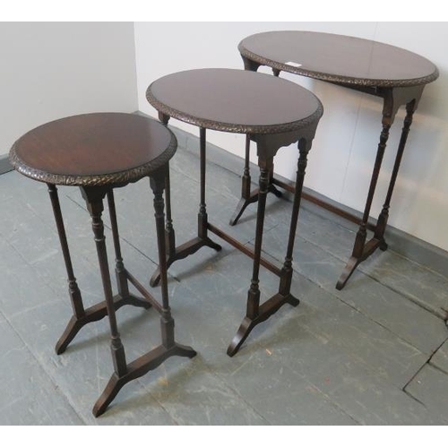 820 - An Edwardian mahogany nest of three oval tables by Maple & Co, with foliate carved borders, on turne... 