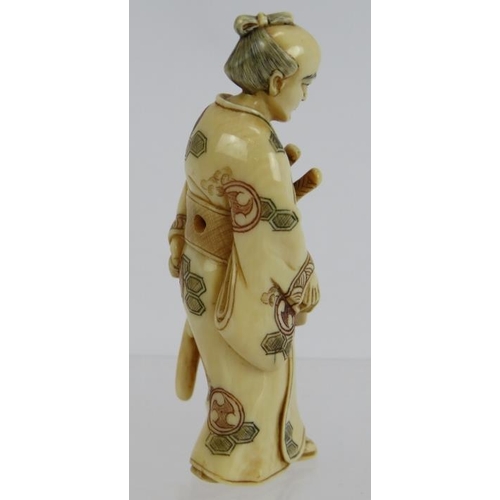 13 - A finely carved Japanese ivory Netsuke, Meiji period of a standing Samurai, decorated in red and bla... 