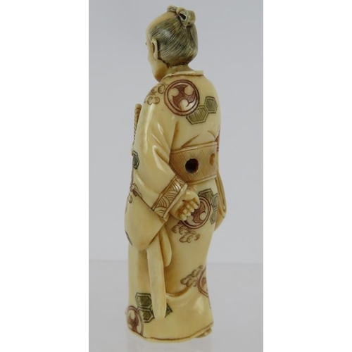 13 - A finely carved Japanese ivory Netsuke, Meiji period of a standing Samurai, decorated in red and bla... 