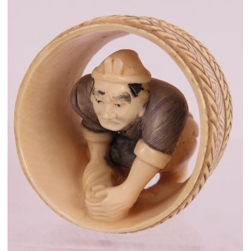 15 - A finely carved Japanese ivory Netsuke of a cooper working in a barrel. Height: 4.8cm.  Signed to ba... 