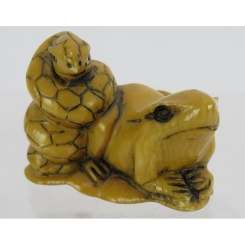 24 - A Japanese carved ivory Netsuke, early 20th century featuring a frog and snake sitting on a lily pad... 