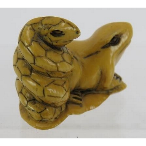 24 - A Japanese carved ivory Netsuke, early 20th century featuring a frog and snake sitting on a lily pad... 