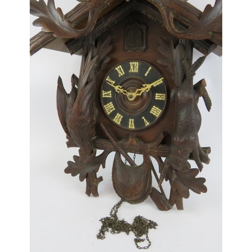 54 - A large Black Forest style cuckoo clock with carved hunting themed animals. Height 60cm.
Condition r... 