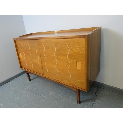 701 - A mid-century 1950s walnut & elm sideboard for Heal’s, the sliding doors opening onto a fitted inter... 