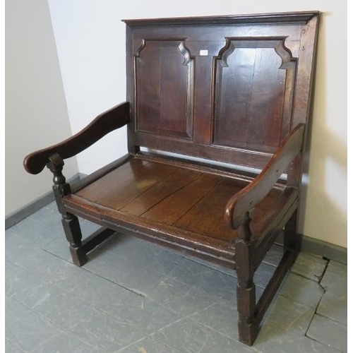 702 - A 17th century and later oak settle, with fielded back panels, on turned and block supports with str... 