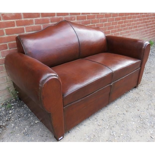 723 - A French Art Deco ‘moustache back’ two-seater sofa upholstered in tobacco brown leather, on block fe... 