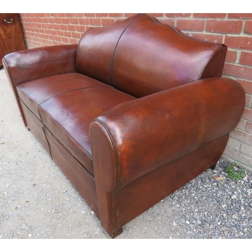 723 - A French Art Deco ‘moustache back’ two-seater sofa upholstered in tobacco brown leather, on block fe... 