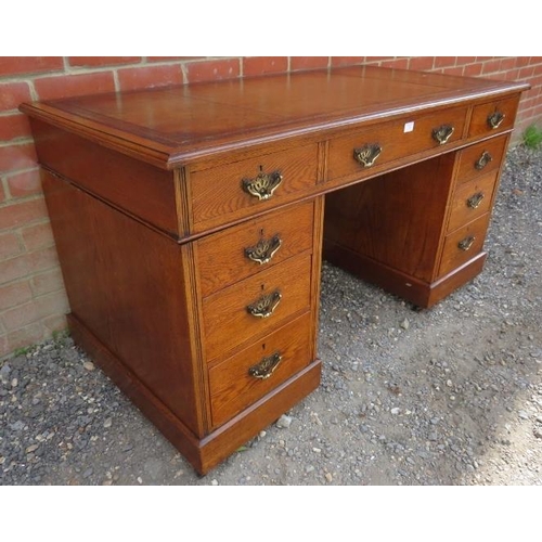 724 - An Edwardian medium oak pedestal desk with inset gilt tooled leather writing surface, housing a conf... 