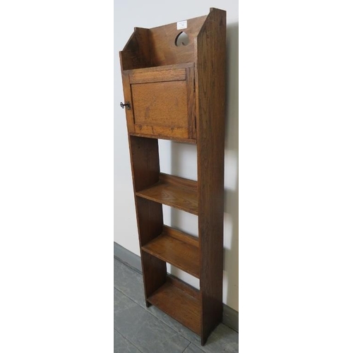 730 - An Arts & Crafts elm and oak narrow open bookcase of three shelves, with locking cupboard and pierce... 