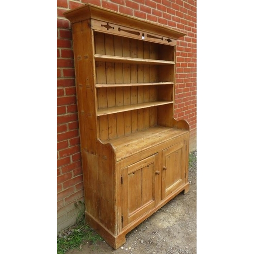 760 - An antique pine kitchen dresser with carved and pierced cornice over plate rack shelving, over a dou... 