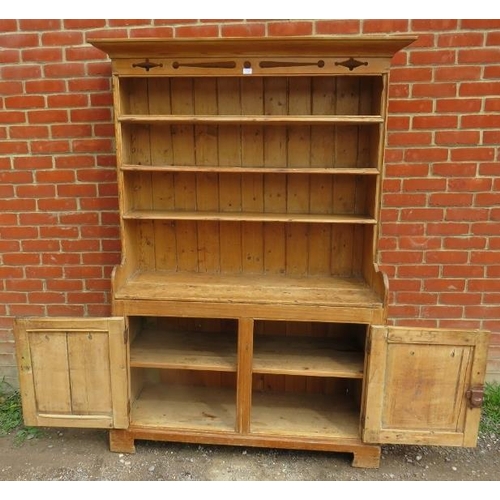 760 - An antique pine kitchen dresser with carved and pierced cornice over plate rack shelving, over a dou... 