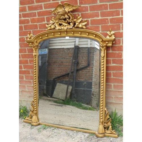 807 - An ornate giltwood bevelled overmantle mirror in the Regency taste, surmounted by a carved eagle amo... 