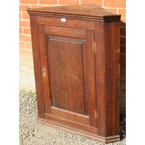 818 - A Georgian oak wall hanging corner cupboard with fielded panelled door and brass lock escutcheon, co... 