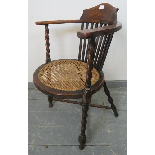 712 - An Arts & Crafts oak oval elbow chair, with bergere seat and barley twist uprights united by a bobbi... 