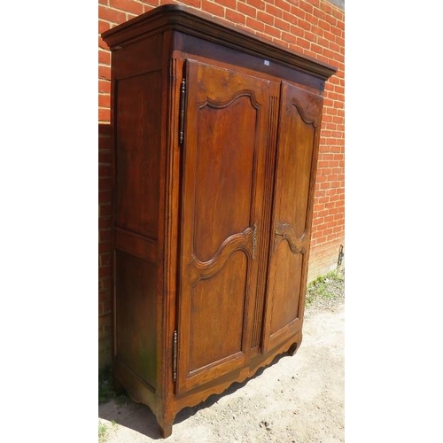 716 - An 18th century French oak armoire, the panelled doors opening onto a hanging rail, on ogee supports... 