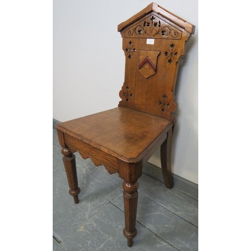 733 - A Victorian medium oak hall chair with carved and pierced backrest and applied shield decoration, on... 