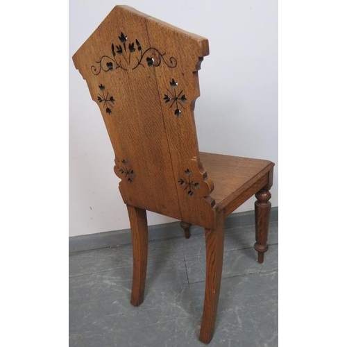 733 - A Victorian medium oak hall chair with carved and pierced backrest and applied shield decoration, on... 