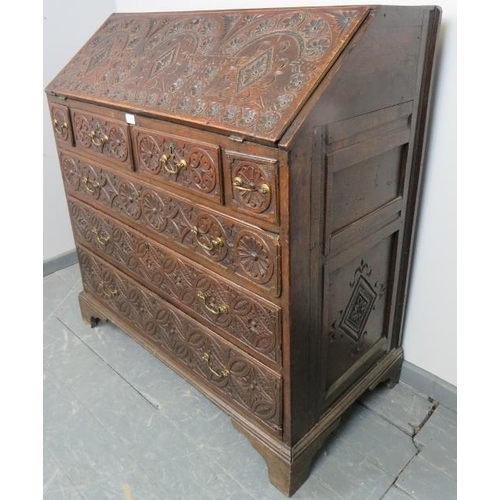 737 - An 18th century oak bureau, featuring extensive relief carving, the fall front opening onto a fitted... 