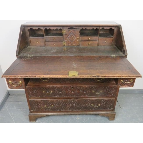 737 - An 18th century oak bureau, featuring extensive relief carving, the fall front opening onto a fitted... 