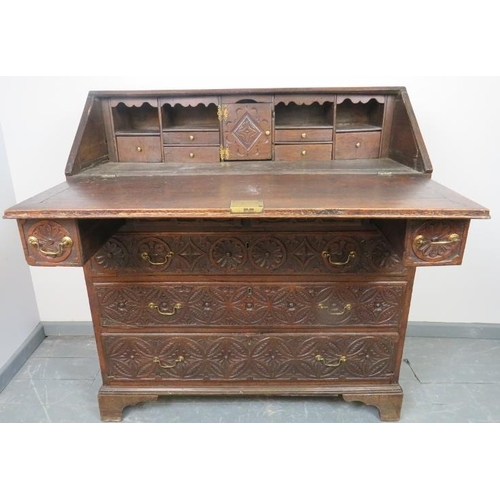 737 - An 18th century oak bureau, featuring extensive relief carving, the fall front opening onto a fitted... 