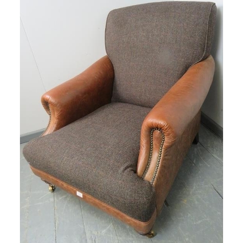 738 - A large club armchair in the manner of Howard & son, upholstered in tan leather with brass studs and... 