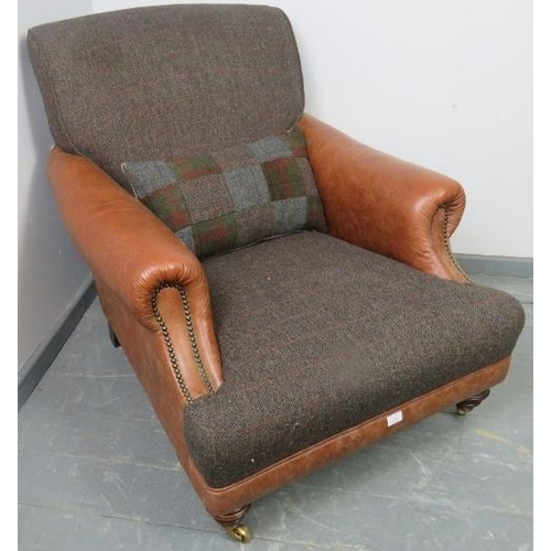 738 - A large club armchair in the manner of Howard & son, upholstered in tan leather with brass studs and... 