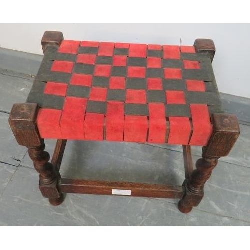 762 - A small vintage oak stool, with black and red strapwork leather seat, on barley twist supports with ... 