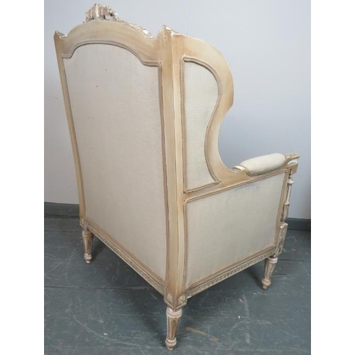 765 - A vintage French wingback armchair in the Louis XV taste, upholstered in a cream material, with reed... 