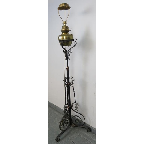 793 - A Victorian wrought iron and brass standard lamp, on ornately scrolled base. Has been converted from... 