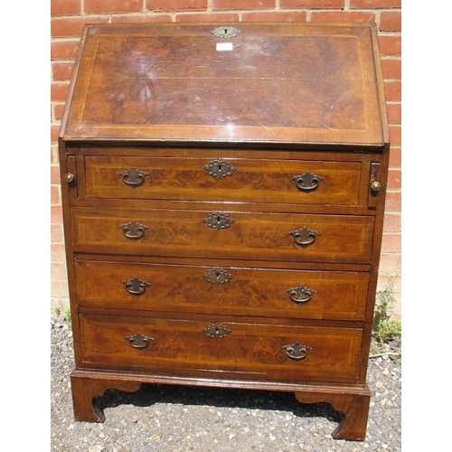 808 - A Georgian Revival walnut bureau, featuring crossbanded inlay, the fall front opening onto a fitted ... 