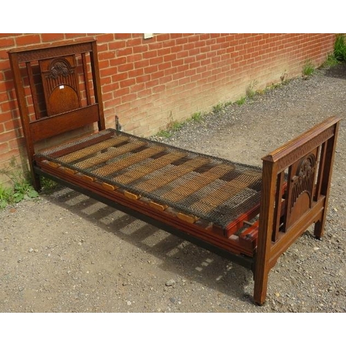 814 - An Edwardian oak single bed with foliate carved head and foot boards and sprung mattress squab. 
Con... 