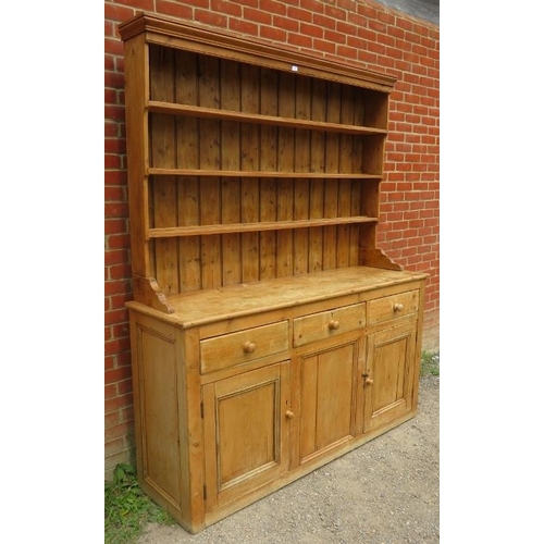 815 - A large antique stripped pine kitchen dresser, with plate rack shelving over a sideboard base contai... 