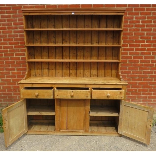 815 - A large antique stripped pine kitchen dresser, with plate rack shelving over a sideboard base contai... 