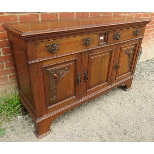 817 - An Art Nouveau carved oak sideboard, housing two short drawers over three cupboards with fitted shel... 