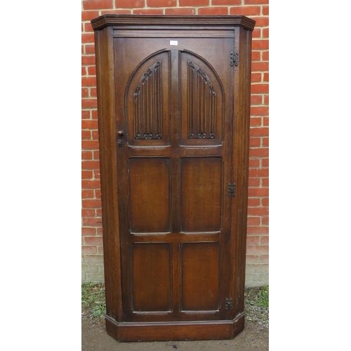 824 - A vintage 18th century style oak freestanding corner cupboard, the panelled door featuring linen fol... 