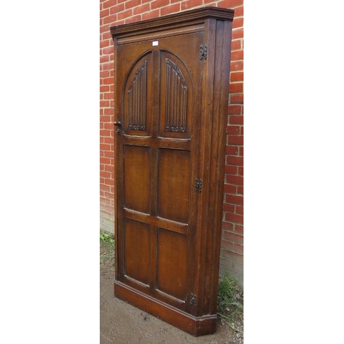 824 - A vintage 18th century style oak freestanding corner cupboard, the panelled door featuring linen fol... 