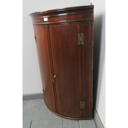 831 - A George III mahogany bow fronted wall hanging corner cupboard, strung with satinwood, with 3 fitted... 