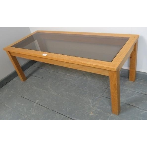 849 - A contemporary light oak rectangular coffee table with smoked glass insert, on square supports. 
Con... 