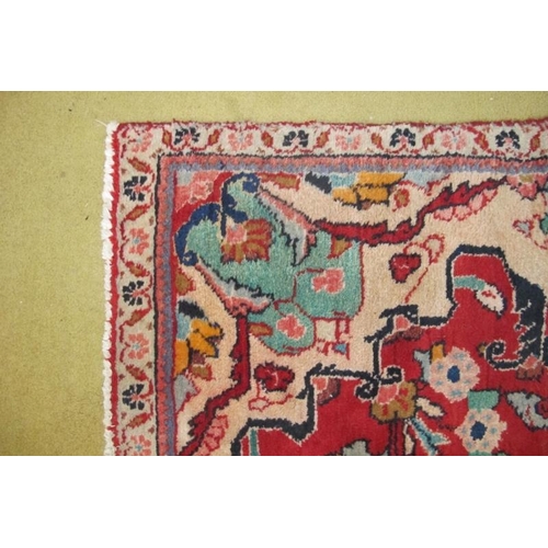 924 - A mid 20th century Persian rug central pattern on red ground. 180cm x 140cm (approx). Some wear to o... 