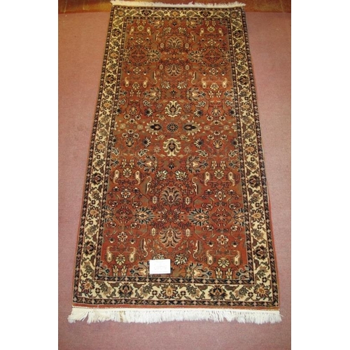 926 - A 20th century rug, a central pattern field on dusky pink ground with a patterned cream border. 205c... 