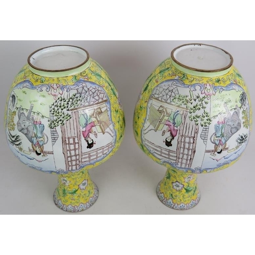 104 - A pair of Chinese Cantonese enamel vases hand decorated with traditional scenes set on a yellow back... 