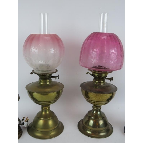 123 - Two brass oil lamps, both etched Cranberry shades and two similar lamps converted to electricity, on... 