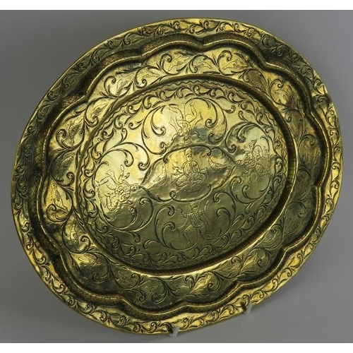 25 - An antique hand beaten Indo-Persian brass dish of oval form with raised rim decorated with birds aro... 