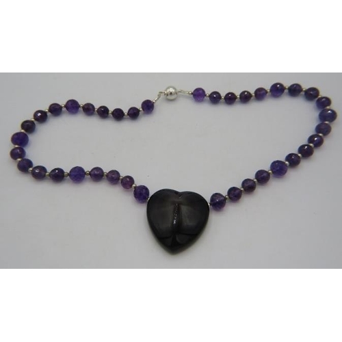 361 - An amethyst necklace interspersed with small white metal beads. The centre of the necklace having a ... 